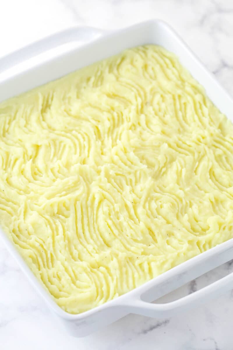 This easy Sheperd's Pie is made of perfectly seasoned ground beef and veggies topped with mashed potatoes and cheese and baked to bubbly. Mashed potatoes spread over meat and vegetable mixture with lines raked through it.