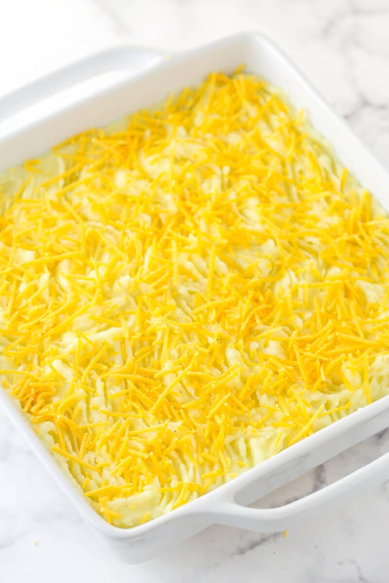 Sprinkling cheddar cheese over shepherd's pie before baking.