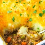 Shepherd's pie in a baking dish with a serving spoon taking a piece out of it.