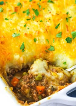 Shepherd's pie in a baking dish with a serving spoon taking a piece out of it.