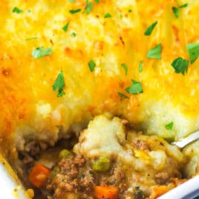 Shepherd's pie in a baking dish with a serving spoon taking a piece out of it.
