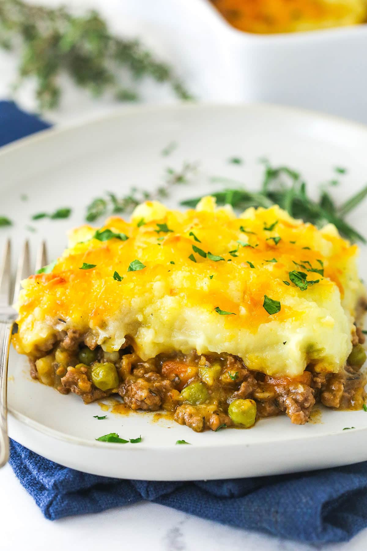 This easy Sheperd's Pie is made of perfectly seasoned ground beef and veggies topped with mashed potatoes and cheese and baked to bubbly. A slice of shepherd's pie on a plate.