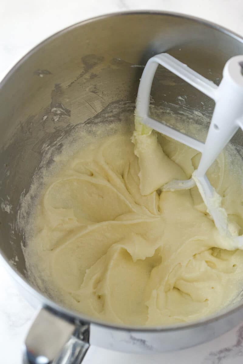 Adding sour cream and vanilla extract to creamed butter and sugar for cupcake batter.