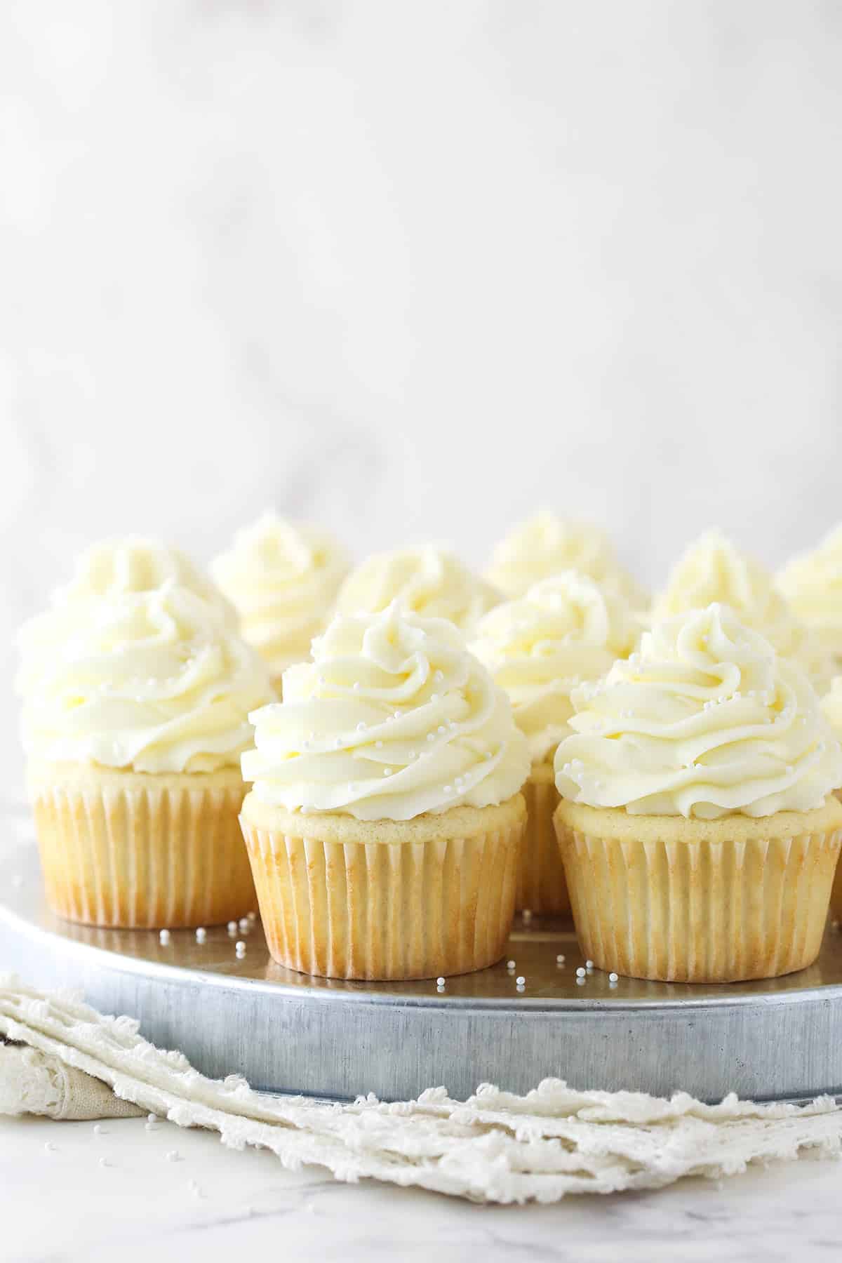 Zoom out of white cupcakes on a serving tray.