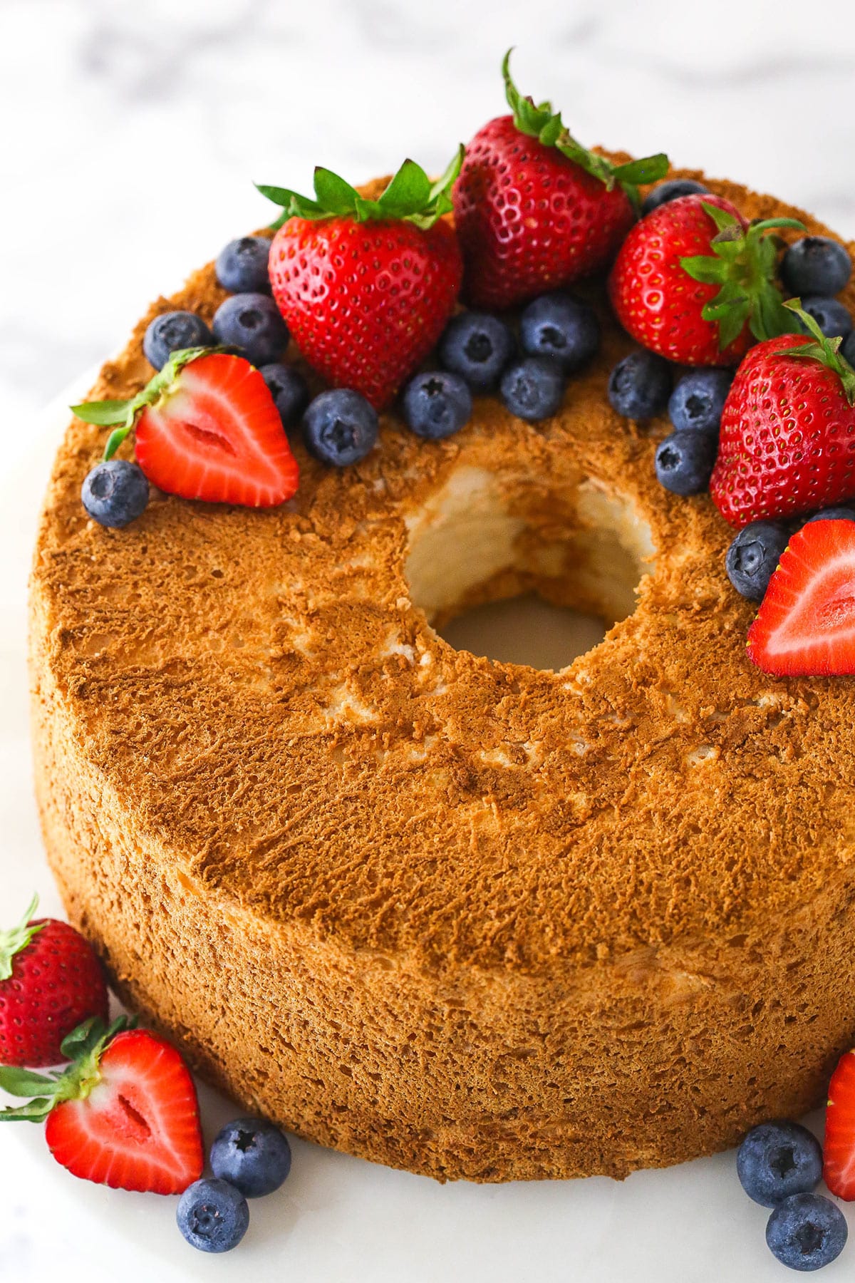 Overhead of angel food cake topped with and surrounded by fresh berries.