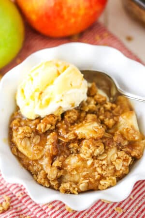 A single serving of Apple Crisp with a scoop of vanilla ice cream in a white bowl with a spoon