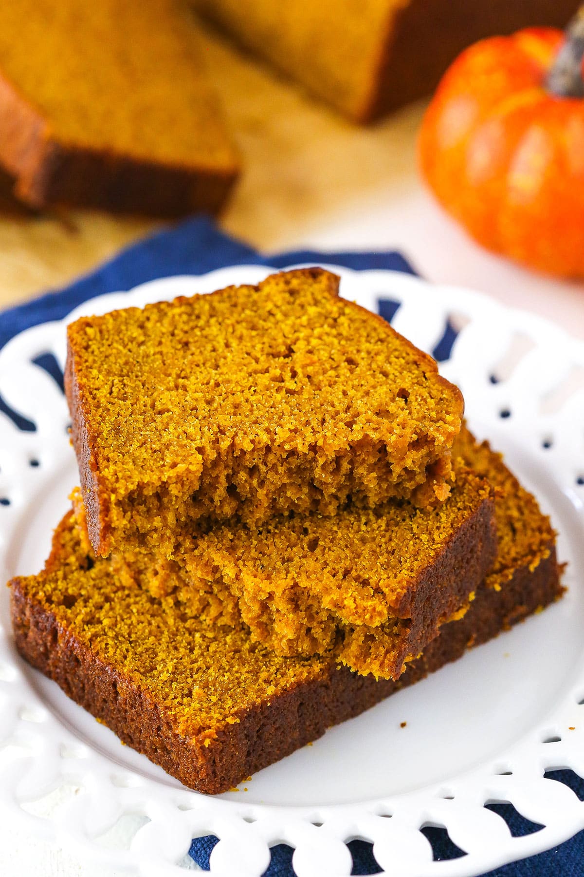 Two halves of Pumpkin Bread on top of another slice of Pumpkin Bread on a white plate