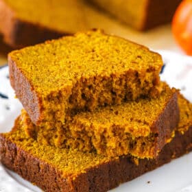Two halves of Pumpkin Bread on top of another slice of Pumpkin Bread on a white plate