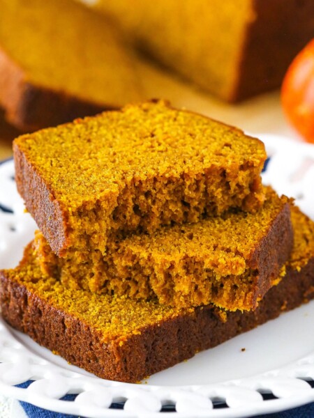 Two halves of Pumpkin Bread on top of another slice of Pumpkin Bread on a white plate