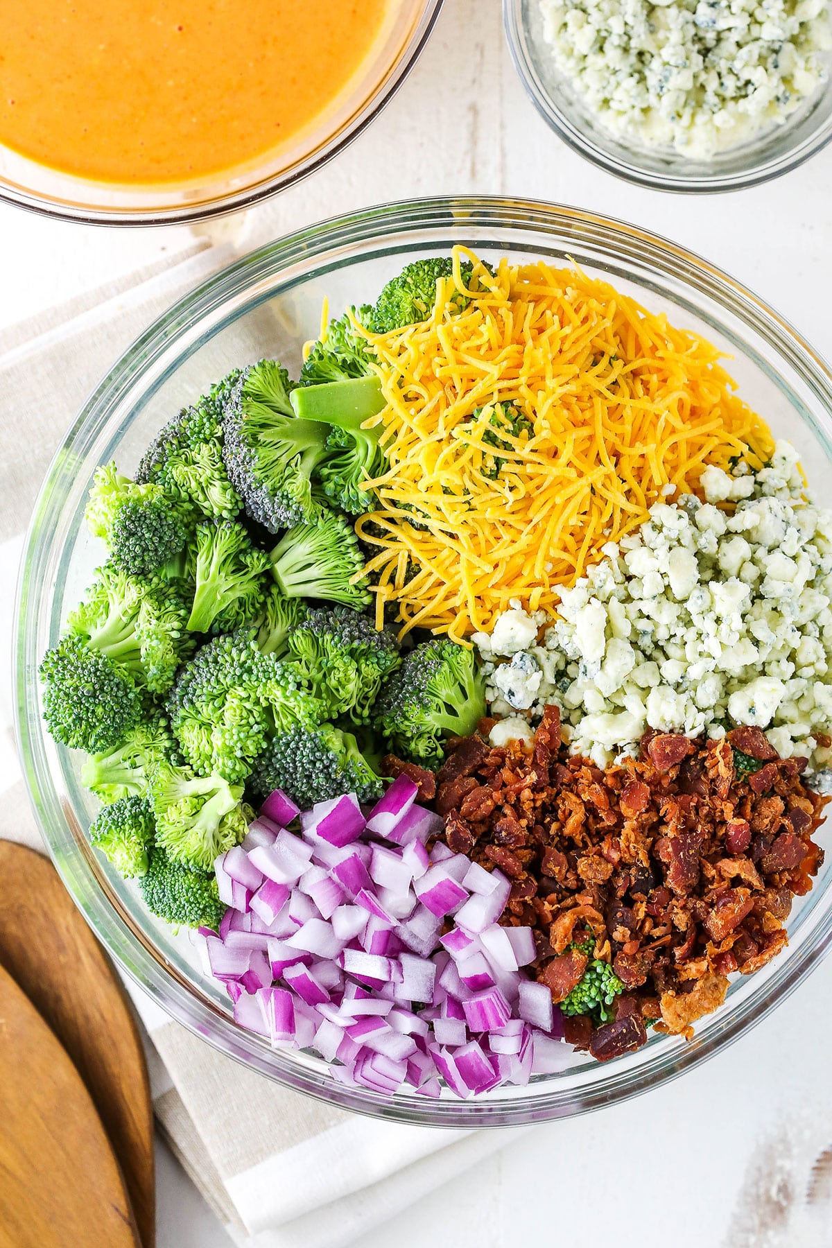 Buffalo Broccoli Salad ingredients in a clear glass bowl on a white table