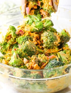 Buffalo Broccoli Salad ingredients being mixed together in a clear glass bowl