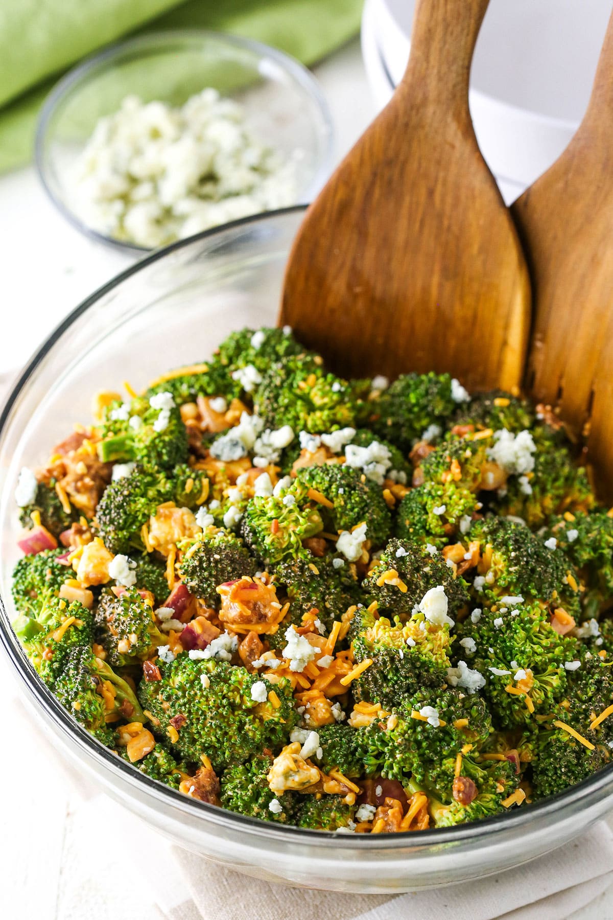 Buffalo Broccoli Salad with wooden serving spoons in a clear glass bowl