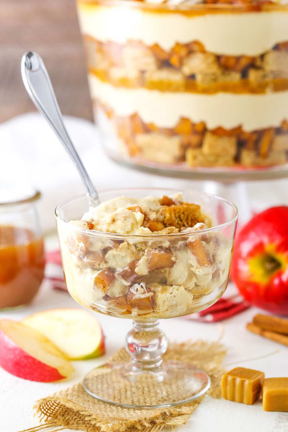 A serving of Caramel Apple Cheesecake Blondie Trifle in a glass bowl with a spoon