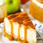 A slice of Caramel Apple Cheesecake next to a fork on a white plate