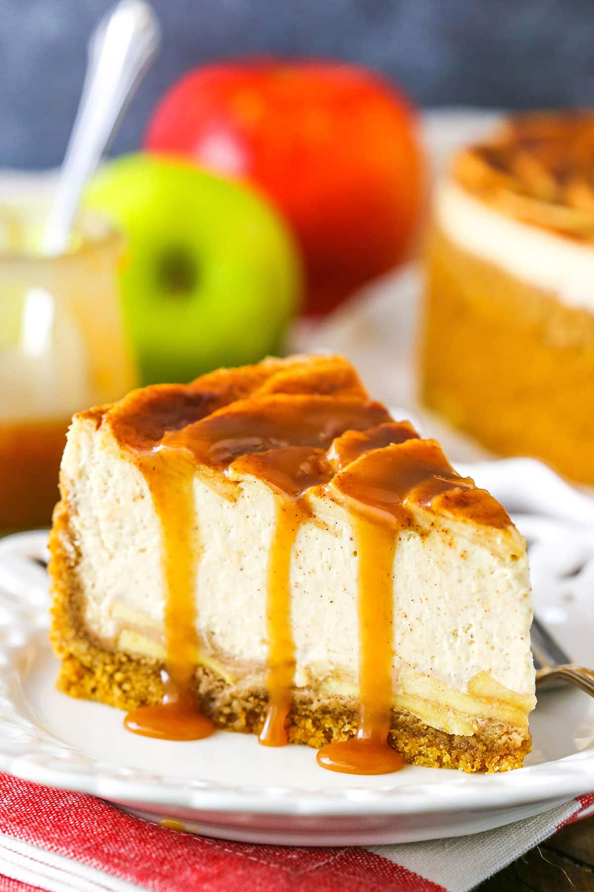 A slice of Caramel Apple Cheesecake next to a fork on a white plate
