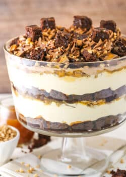 Side view of Caramel Cheesecake Brownie Trifle in a clear glass cake stand