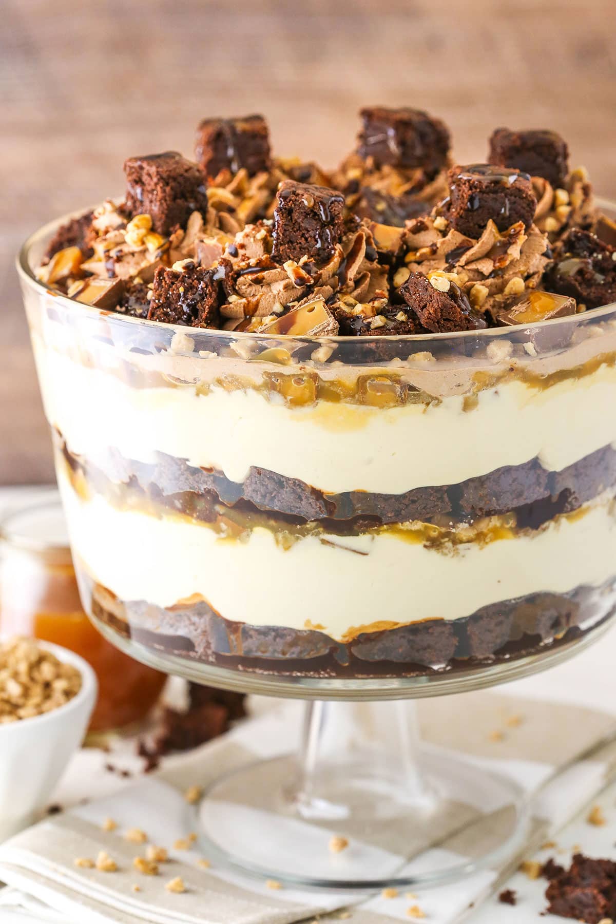 Side view of Caramel Cheesecake Brownie Trifle in a clear glass cake stand