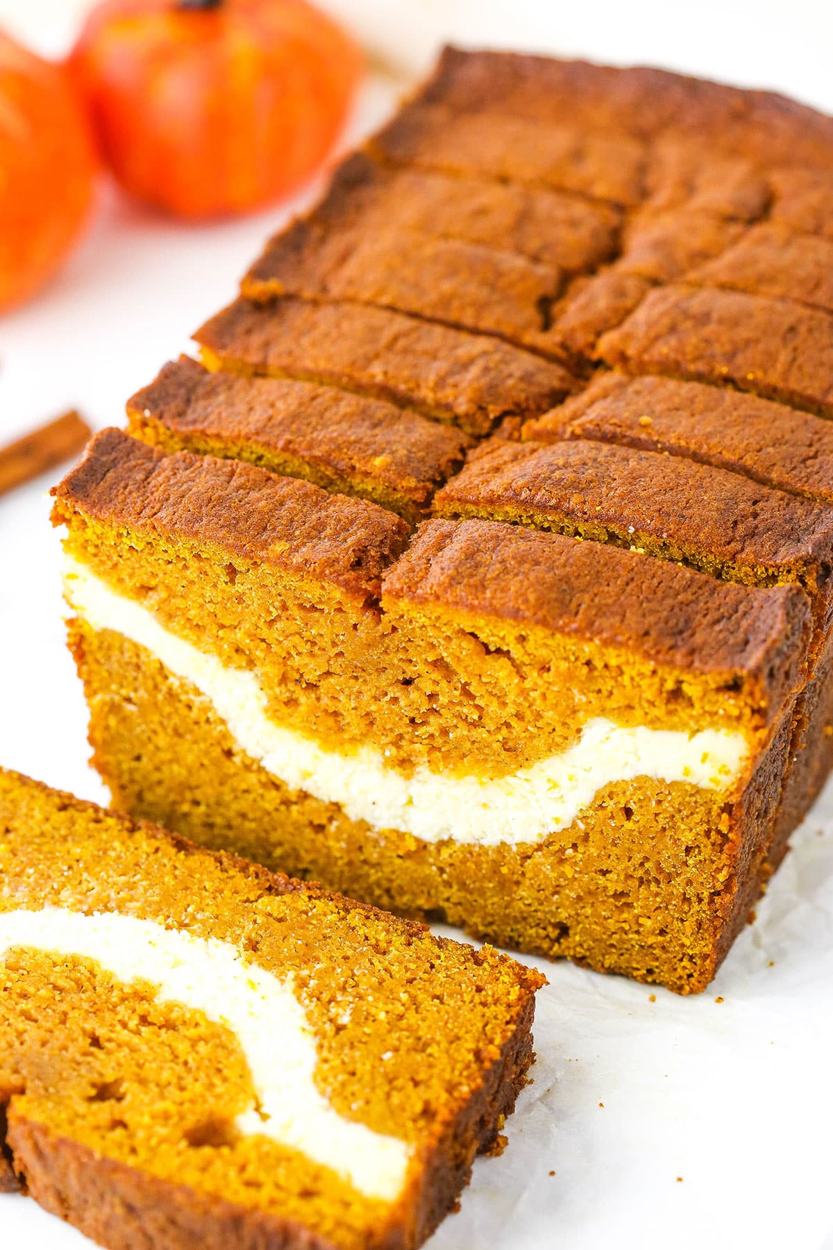 This Cheesecake Swirl Pumpkin Bread has a layer of cheesecake running through the best moist pumpkin bread! It's delicious and takes pumpkin bread to a whole new level! Side view of Cheesecake Swirl Pumpkin Bread sliced with the front slice removed