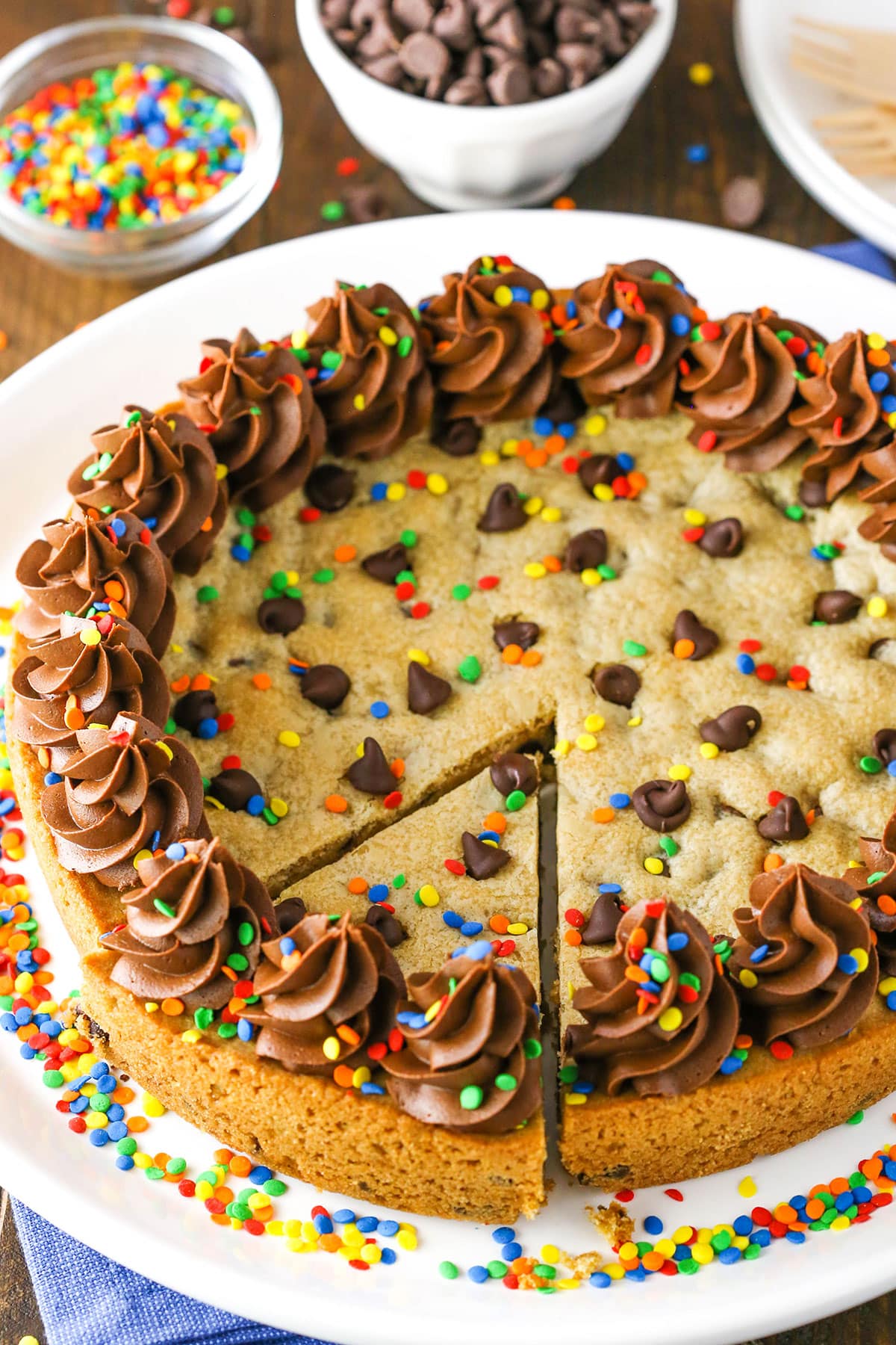 A full Chocolate Chip Cookie Cake with a slice cut out on a white plate