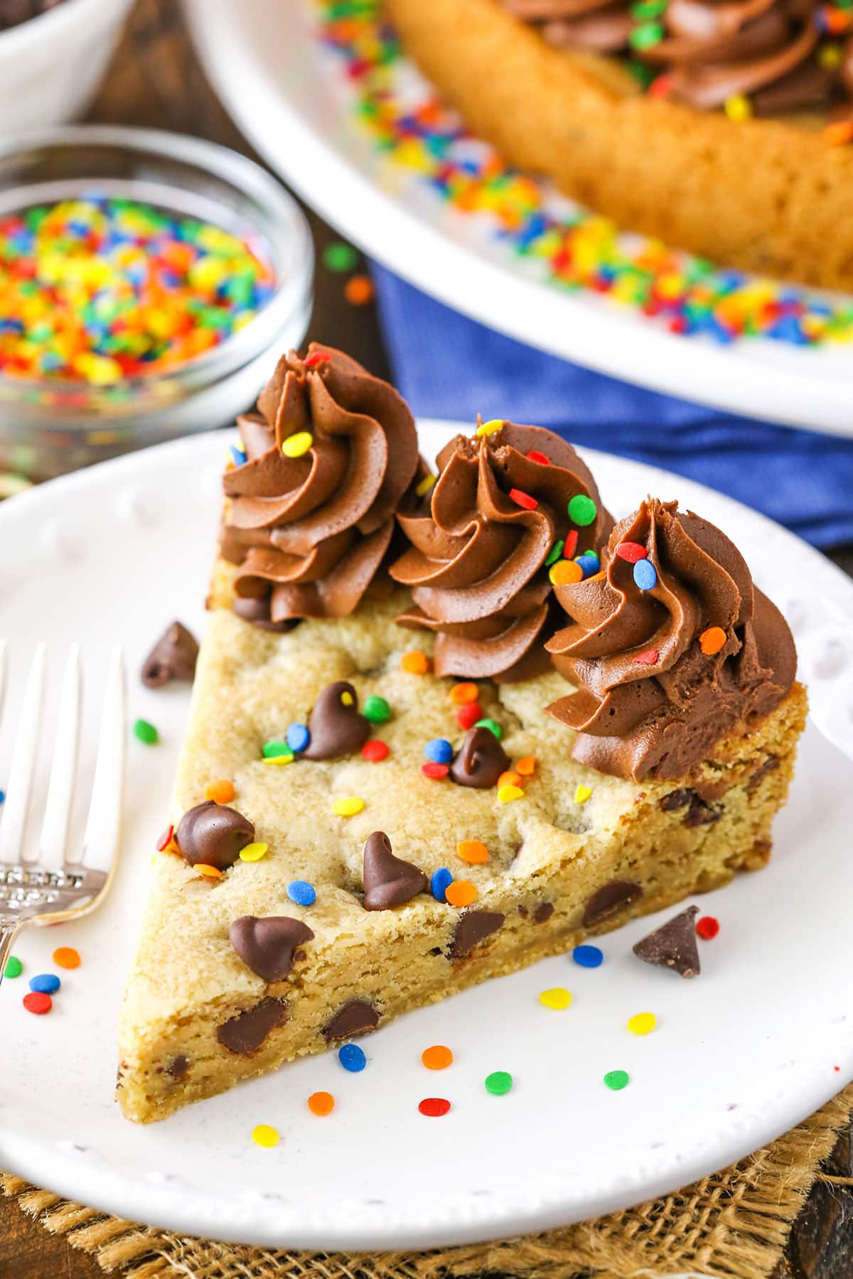 A slice of Chocolate Chip Cookie Cake with a fork on a white plate