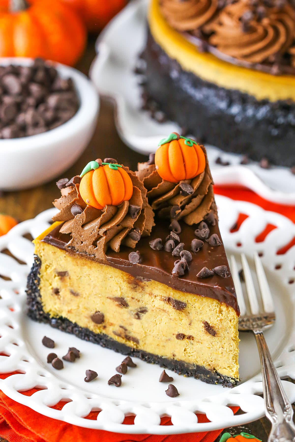 A slice of Chocolate Chip Pumpkin Cheesecake next to a silver fork on a white plate