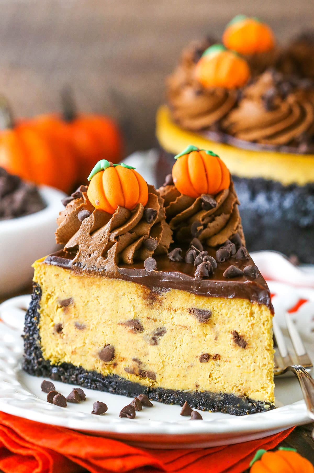 A slice of Chocolate Chip Pumpkin Cheesecake next to a silver fork on a white plate