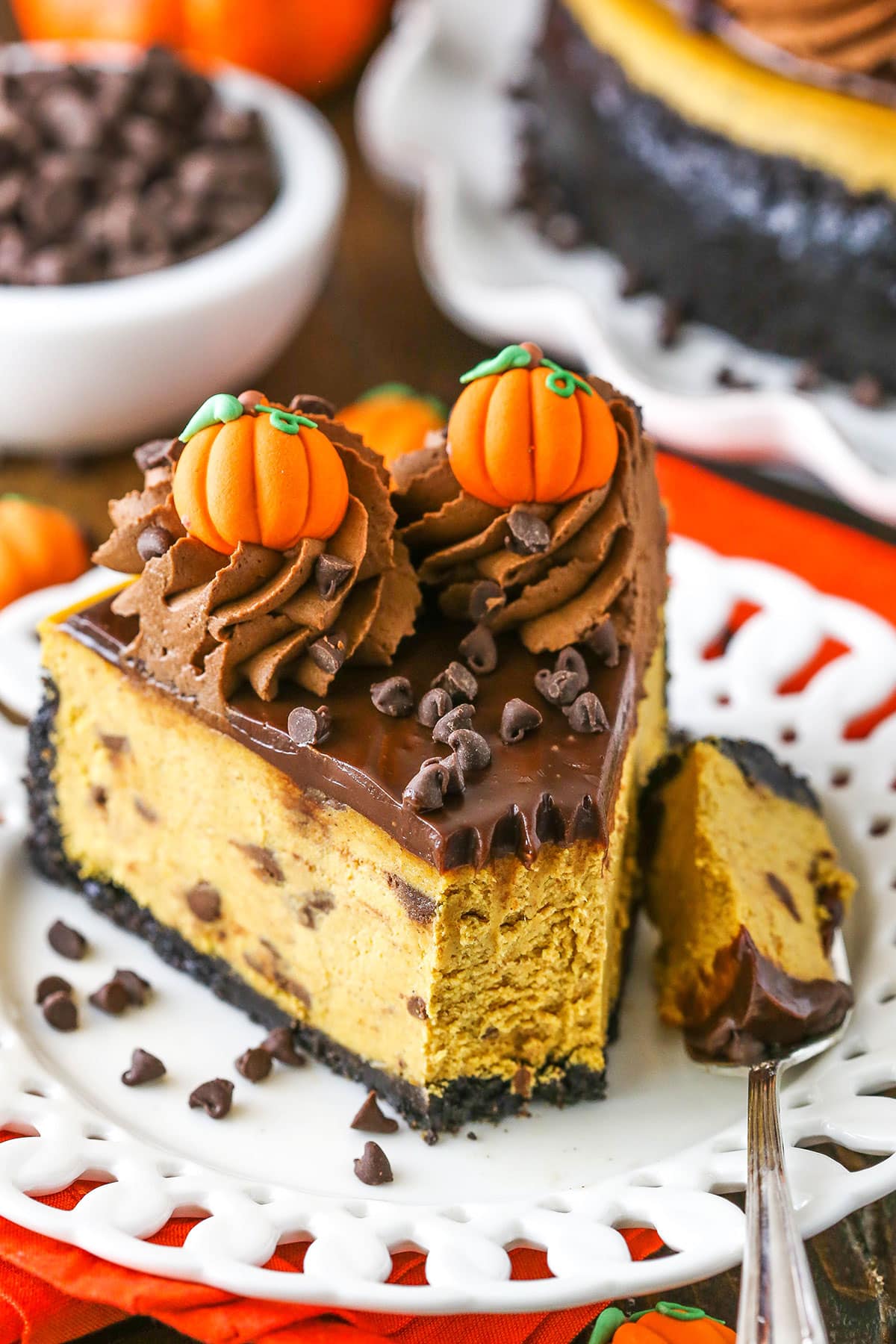 A slice of Chocolate Chip Pumpkin Cheesecake with a bite removed on a white plate