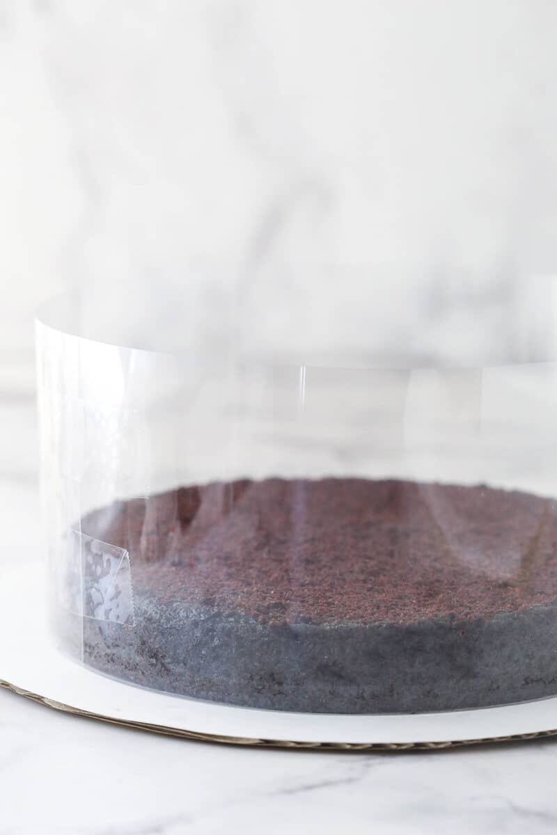 Wrapping a cake collar around a layer of chocolate cake.
