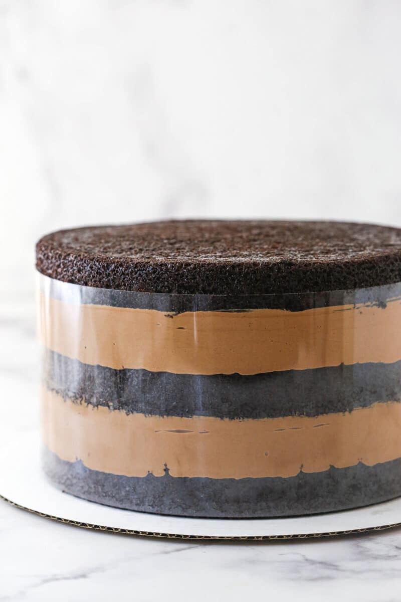 Unfrosted chocolate mousse cake in a clear cake collar.