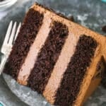 A slice of chocolate mousse cake on a plate with a fork near a bowl of chocolate chips.