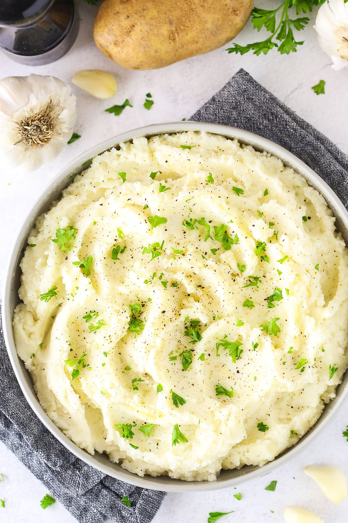 Overhead view of Chunky Garlic Mashed Potatoes in a white bowl on a white table top