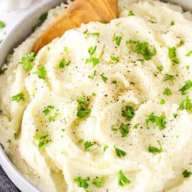 Chunky garlic mashed potatoes in a bowl with a wooden spoon.