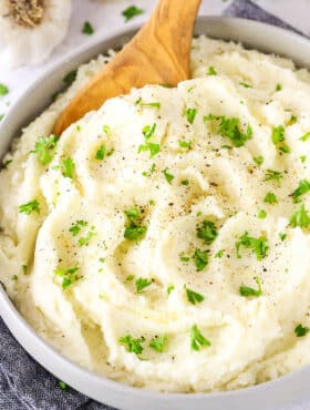 Chunky Garlic Mashed Potatoes in a white bowl with a wooden spoon