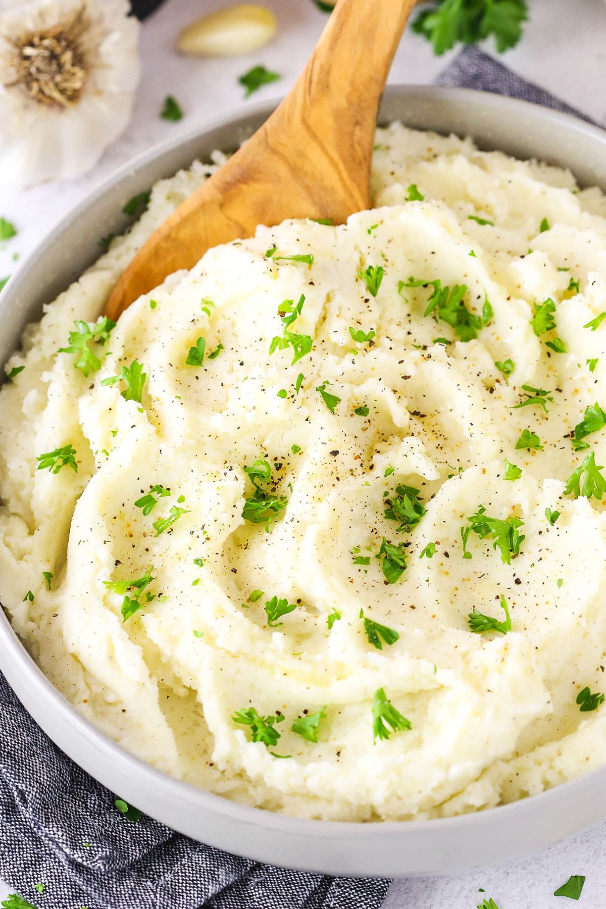 Chunky Garlic Mashed Potatoes in a white bowl with a wooden spoon