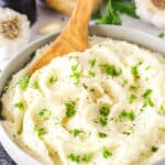 Chunky Garlic Mashed Potatoes in a white bowl with a wooden spoon