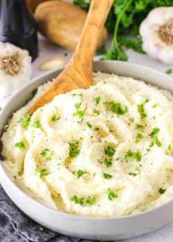 Chunky Garlic Mashed Potatoes in a white bowl with a wooden spoon