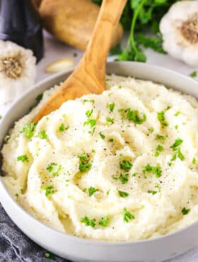 Chunky Garlic Mashed Potatoes in a white bowl with a wooden spoon