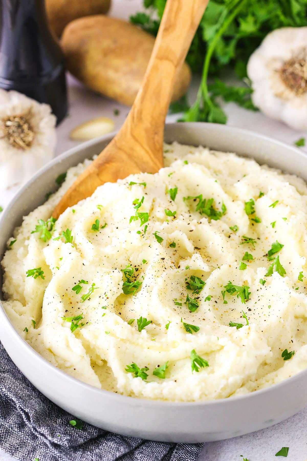 Chunky Garlic Mashed Potatoes in a white bowl with a wooden spoon