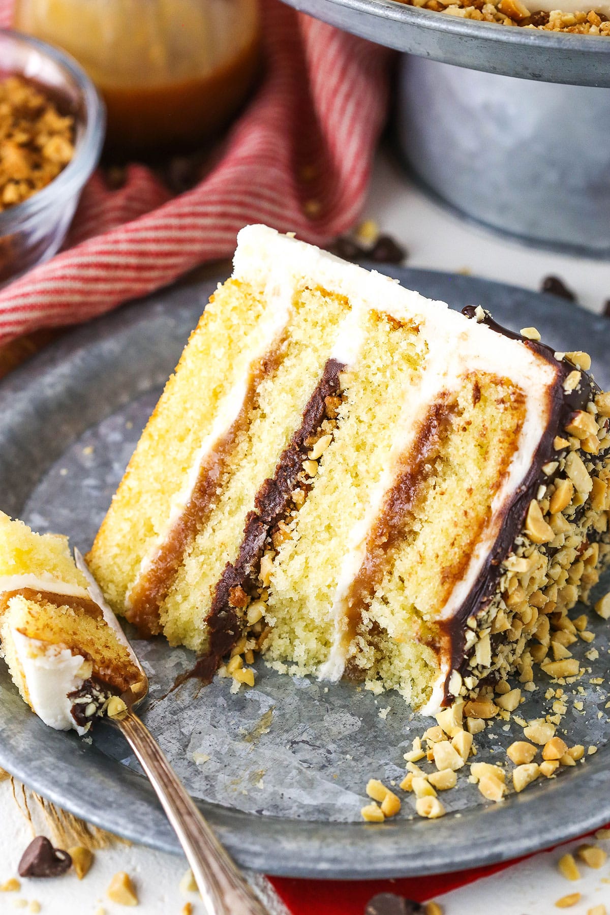 A slice of Drumstick Layer Cake with a bite removed next to a fork on a silver plate