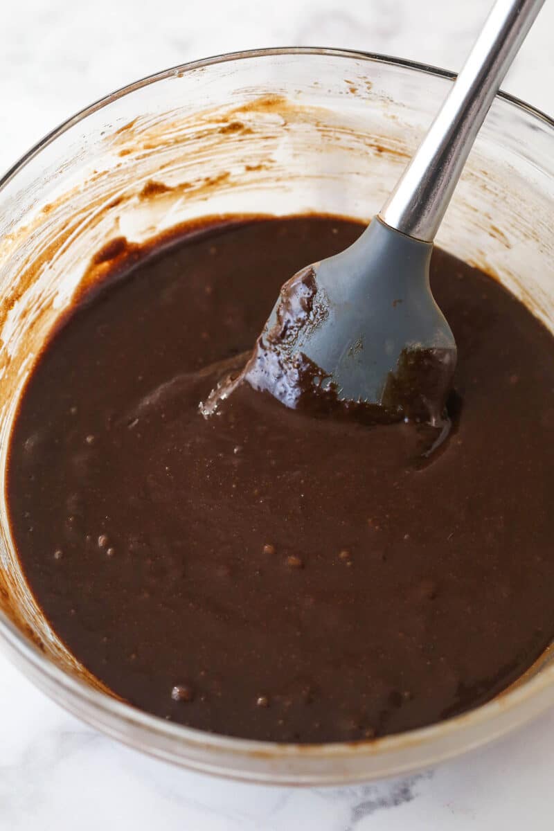 Brownie batter in a mixing bowl with a rubber spatula.