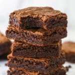 A stack of homemade brownies. The top one has a bite taken out of it.