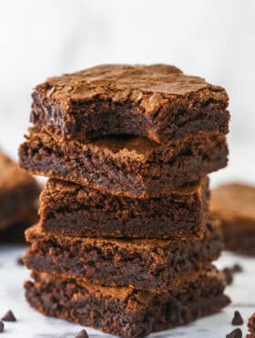 A stack of homemade brownies. The top one has a bite taken out of it.