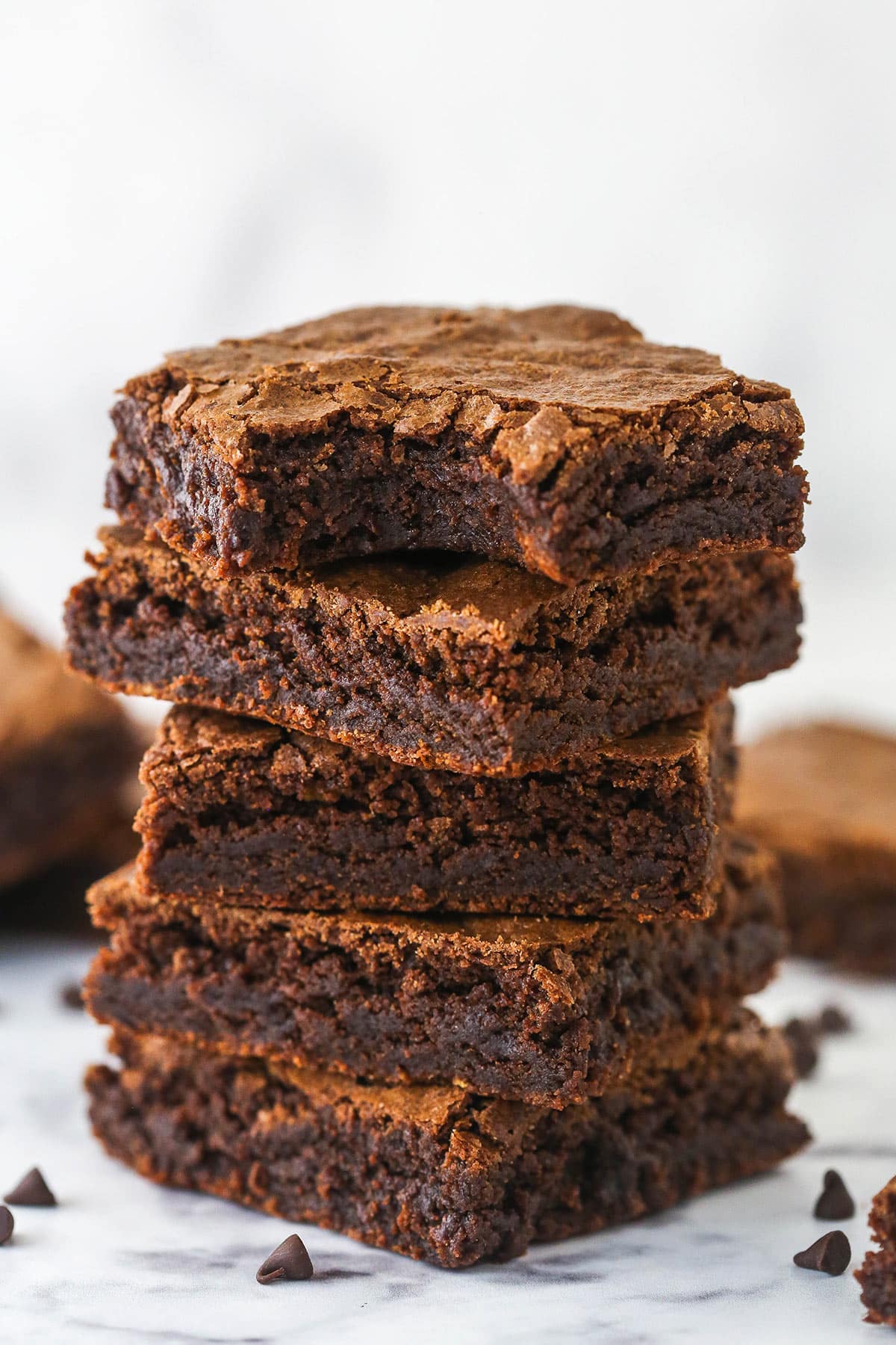 A stack of homemade brownies. The top one has a bite taken out of it.