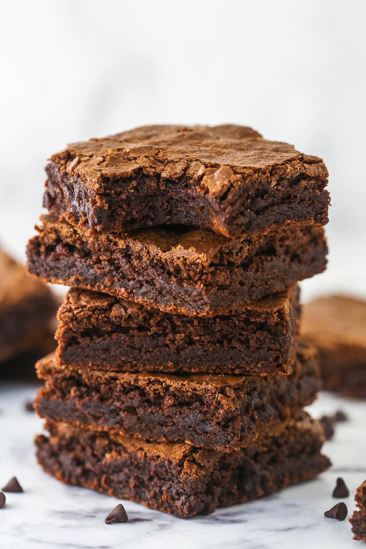 This easy homemade brownies recipe makes wonderfully cakey, fudgy brownies with crave-able, crisp, crackly tops and chewy centers. A stack of homemade brownies. The top one has a bite taken out of it.