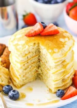 Fluffy Homemade Pancakes stacked with a quarter removed on a white plate