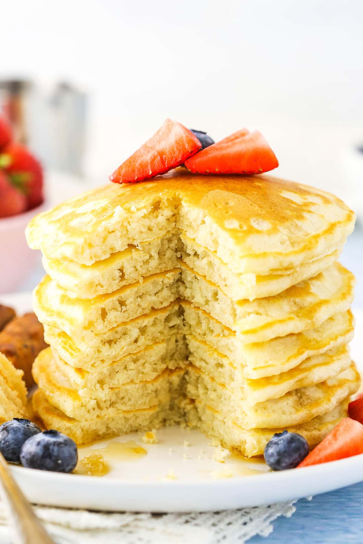 Fluffy Homemade Pancakes stacked with a quarter removed on a white plate