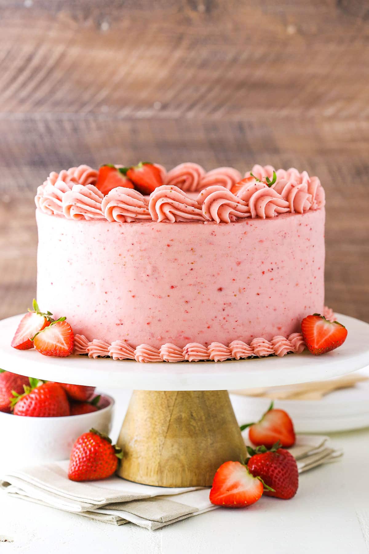 Side view of a Homemade Strawberry Cake with strawberries on a white cake stand