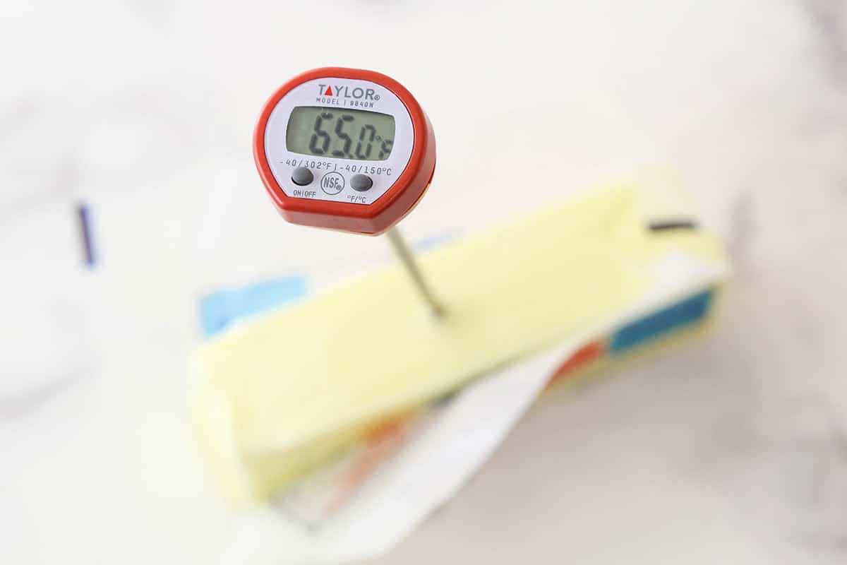 partially opened stick of butter with temperature showing on thermometer