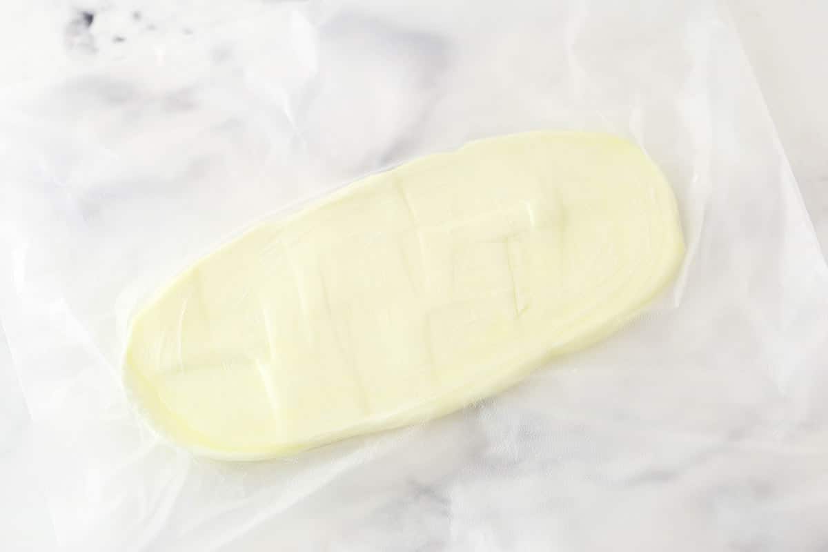 pounded butter between plastic wrap on marble background