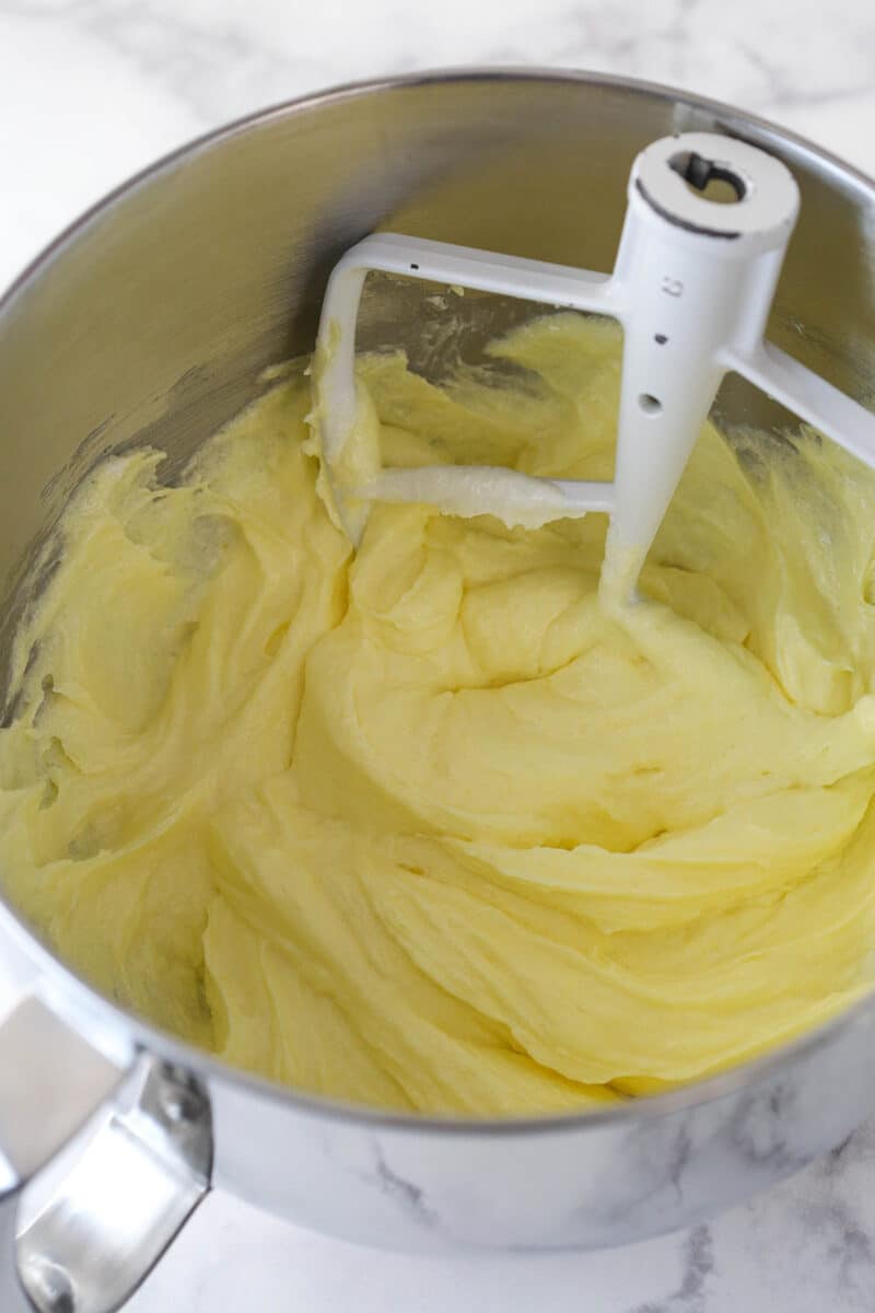 This lemon layer cake is made up of three layers of fluffy lemon cake that are filled and frosted with vibrant lemon cream cheese frosting. Mixing eggs into cake batter.